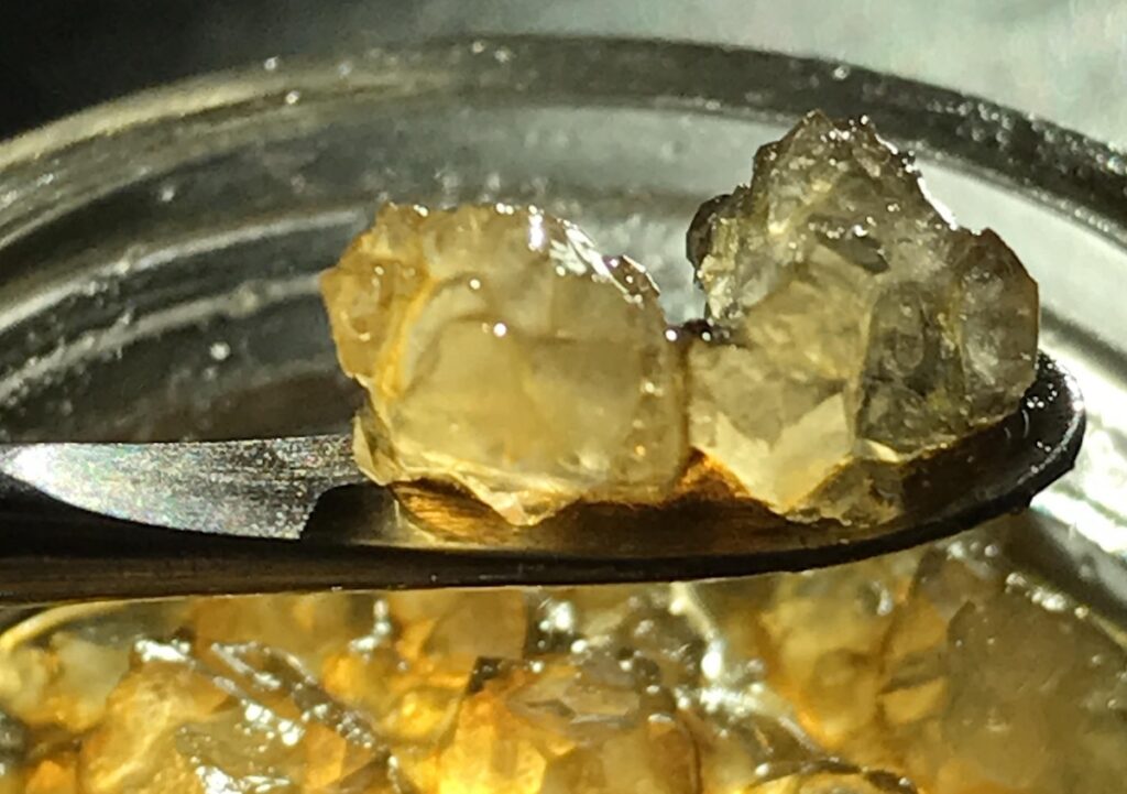 THCA diamonds in a jar next to golden cannabis terpene sauce